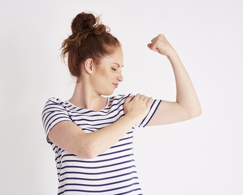 Confident and strong woman showing her bicep at studio shot